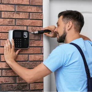 Techniker baut an einem Hauseingang eine Alarmanlage an