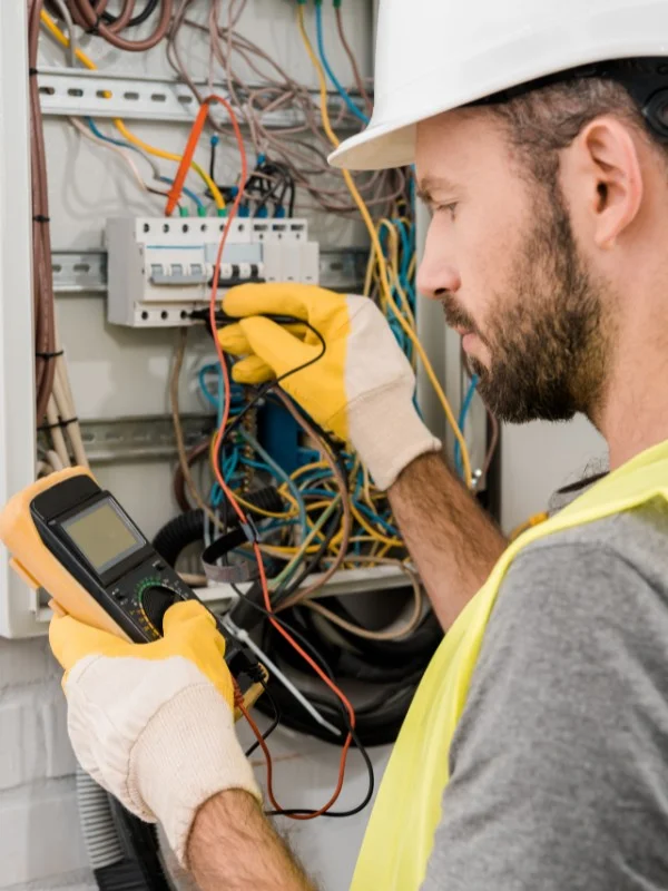 Elektriker misst an einem Schaltkasten den Strom